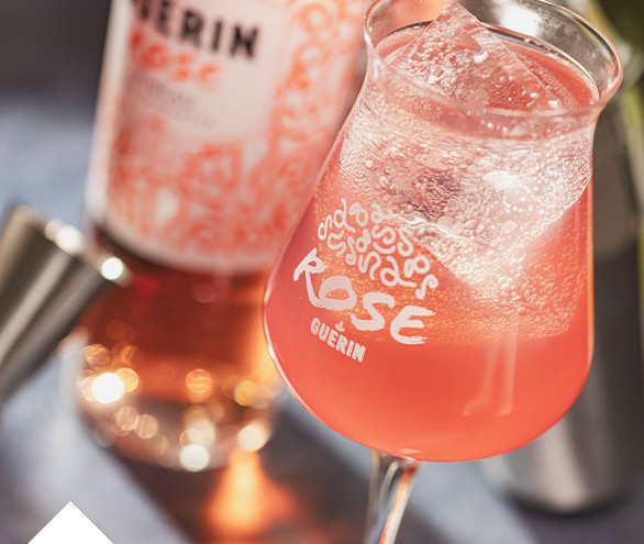 Un verre de cocktail Rose de Guérin à côté d'un Pineau des Charentes Rose.